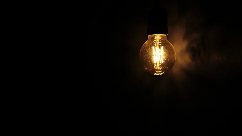 Single lightbulb glowing in dark room