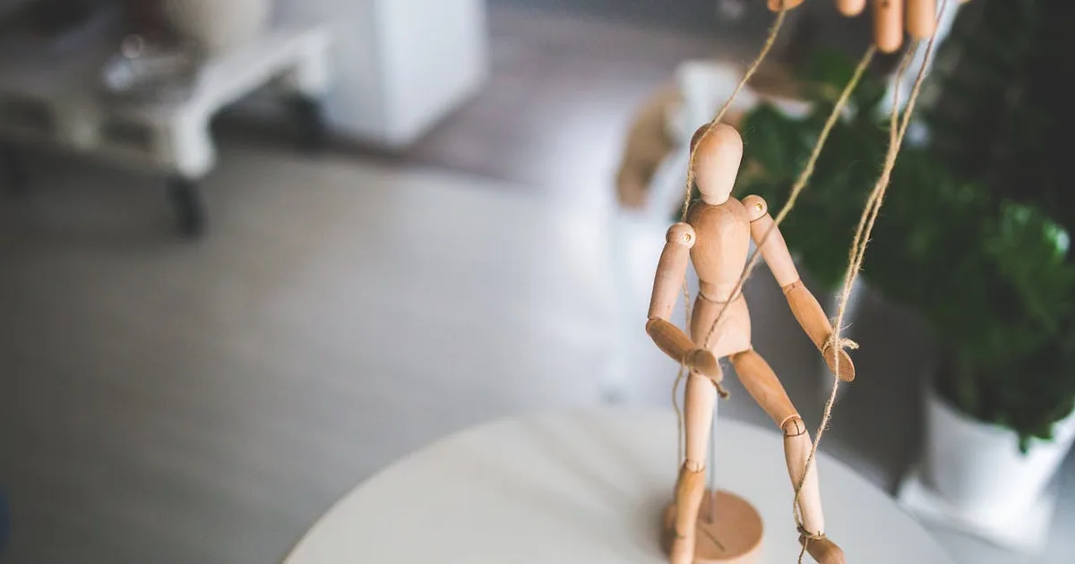 Wooden marionette on strings — crypto KOLs control the market like puppet masters